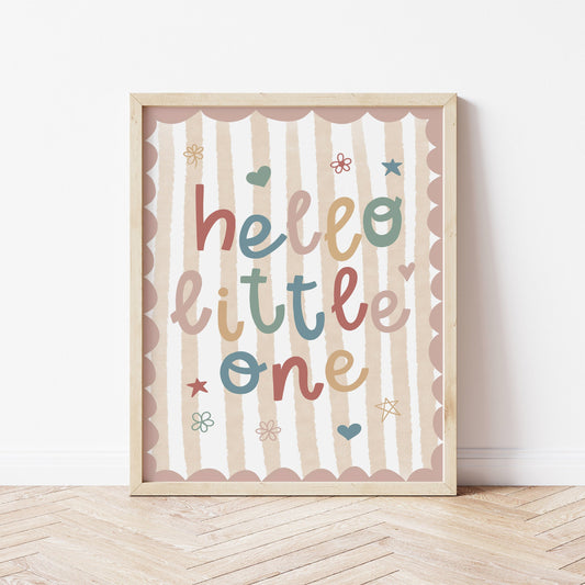 Framed artwork with 'hello little one' text on a striped background, placed on a wooden floor.
