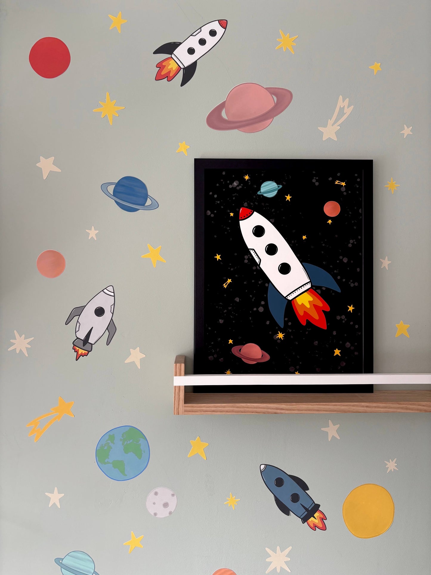 Children's room with space-themed fabric wall stickers and a framed picture of a rocket ship.
