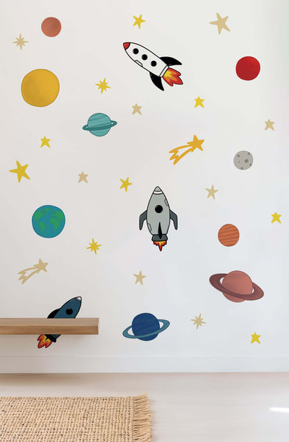 Wall with space-themed wall stickers including rockets, planets, and stars on a white background.