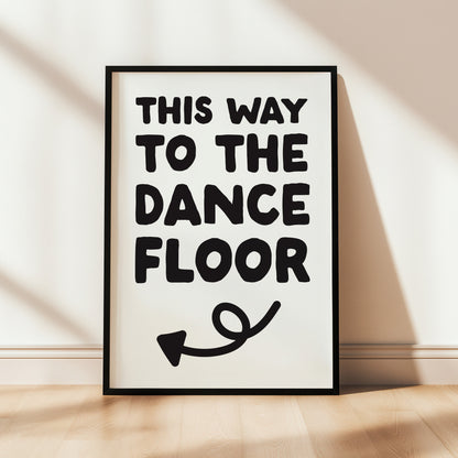 Framed poster with 'This Way to the Dance Floor' text on a wall.